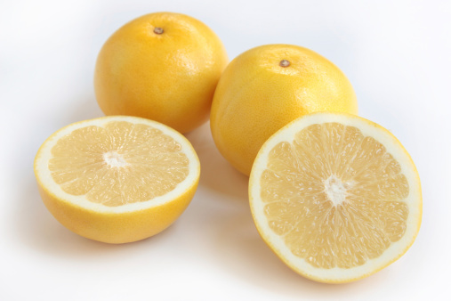 Fresh yellow grapfruit, whole and sliced, on white background