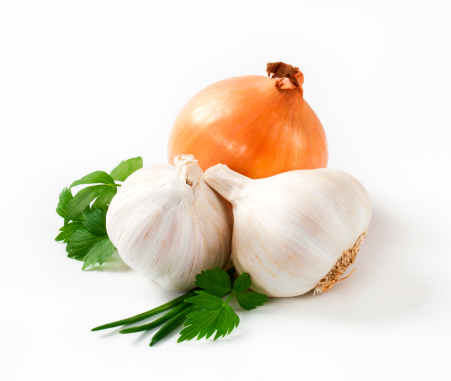 fresh bulbs of garlic and onion with leaves of green herbs