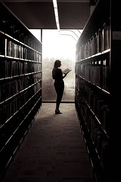 Photo of Silhouette of Woman Reading in Library