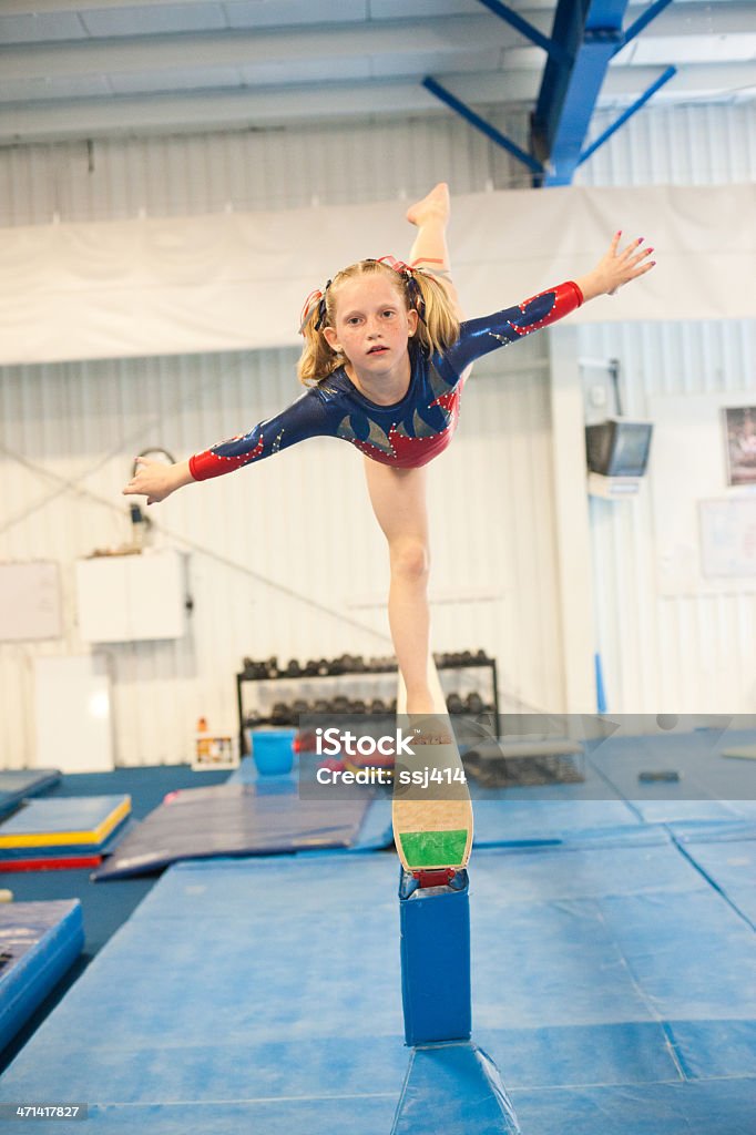 Level five gymnast practicing on beam. Color image of a level 5 gymnast practicing her beam routine. This image has motion blur and grain. Child Stock Photo