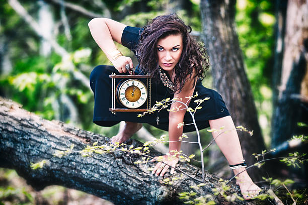 Crazy woman (witch) with old clock in the forest stock photo