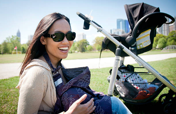 giovane madre l'allattamento al seno il suo bambino in un parco - piedmont park foto e immagini stock