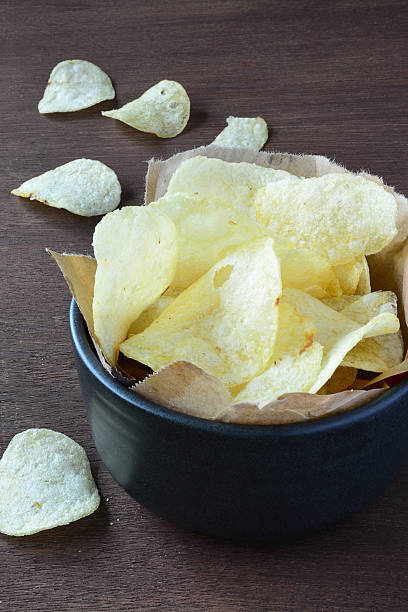 istock Potato chips in black bowl on wooden. 471419702