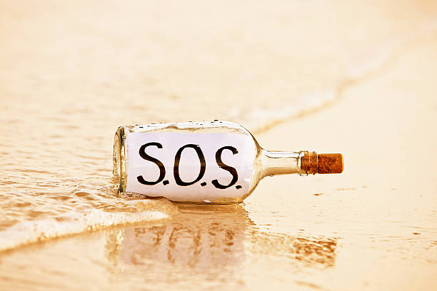 бутылка мыть в surf на шорлайн содержит sos сообщение - stranded message in a bottle island document стоковые фото и изображения