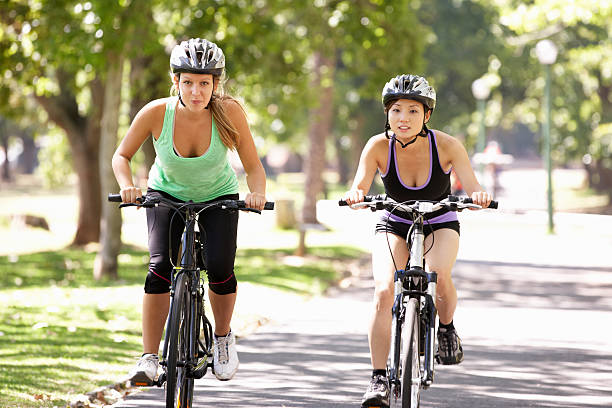 istock Two Women Cycling Through Park 471424919