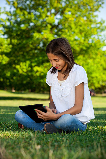 istock Young girl with tablet at park 471426411