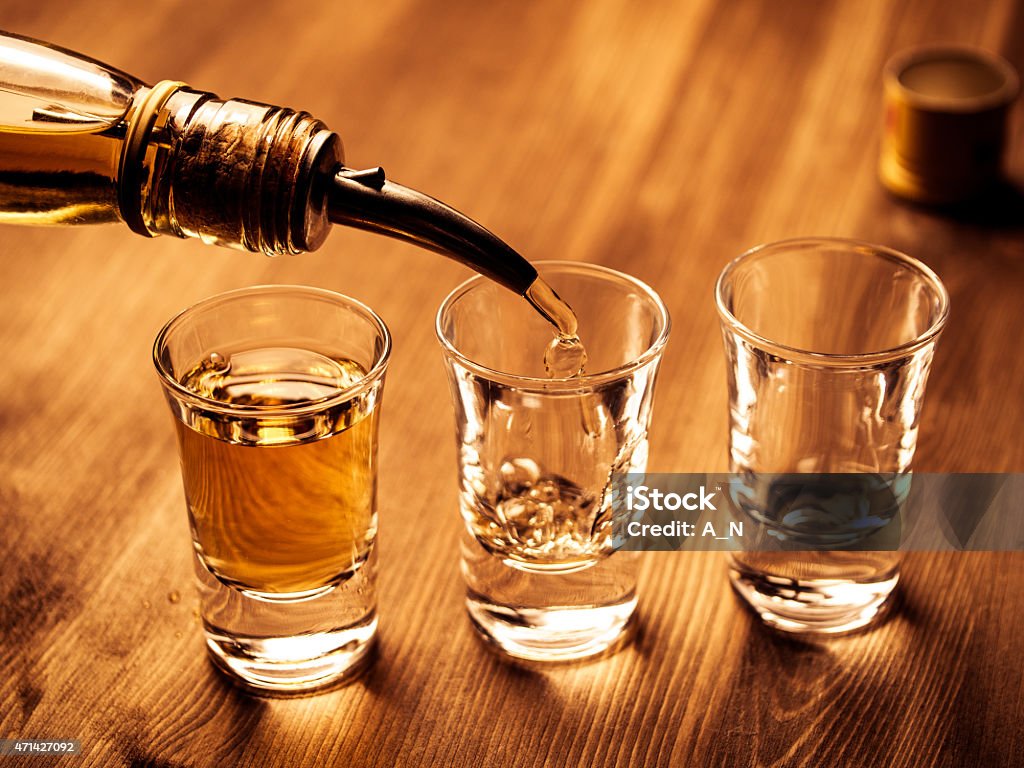 Filling glasses Three shot glasses being filled with a drink Shot Glass Stock Photo