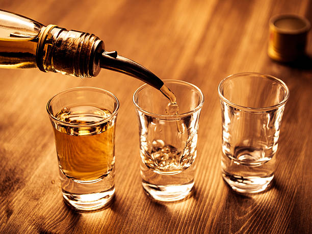 Filling glasses Three shot glasses being filled with a drink shot glass stock pictures, royalty-free photos & images