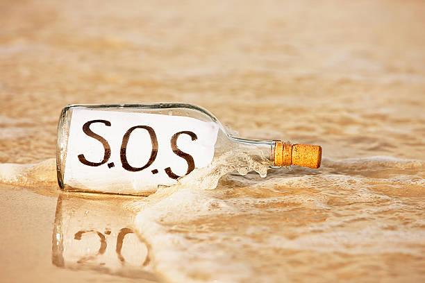 изгой нужна помощь немедленно, поэтому отправка sos сообщение в бутылки - message in a bottle beached bottle desert island стоковые фото и изображения