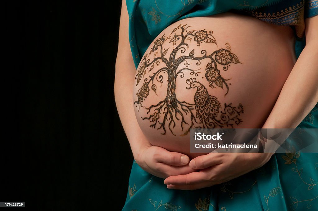 Tree of Life Henna Design on a Woman's Pregnant Belly A color photo of a henna "tree of life" design on a woman's pregnant belly. Henna application in the 8th month of pregnancy is believed to bring an easy birth and healthy child. Pregnant Stock Photo
