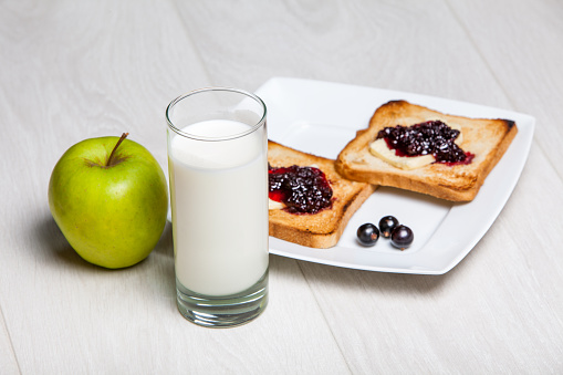 light breakfast - milk and toasts with jam on wooden background