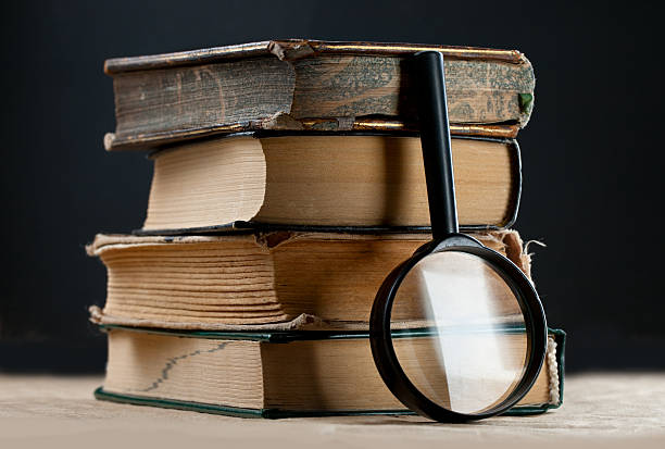 istock Pile of old books with magnifying glass 471430845