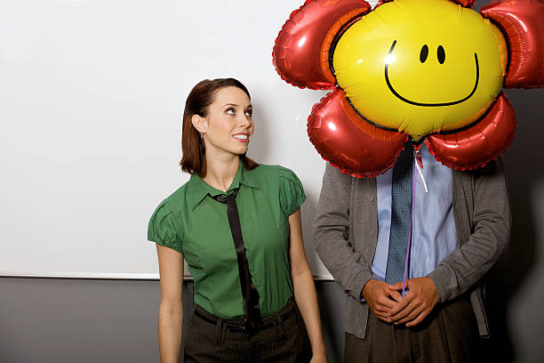 istock Businesswoman looking at balloon over man's face 471432814
