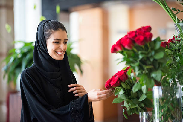 伝統的な中東の女性接触した赤いバラの花瓶 - business travel luxury indoors plant ストックフォトと画像