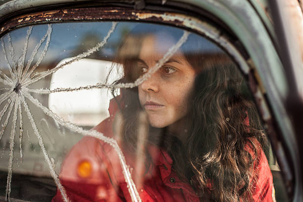 triste mulher cabelos longos em lixo carro com janelas quebradas - broken window glass women - fotografias e filmes do acervo