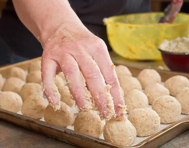 Hand placing the last little balls on a tray. Bowls in the background.