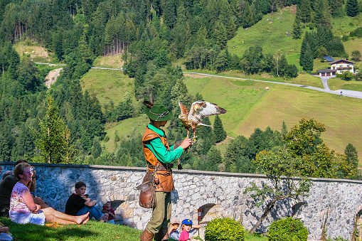 Werfen, Austria - August 31, 2005: man in traditional dress during a falconry demonstration with a hawk at the Hohenwerfen Castle, in the Salzburgerland. People attending the show on the lawn.