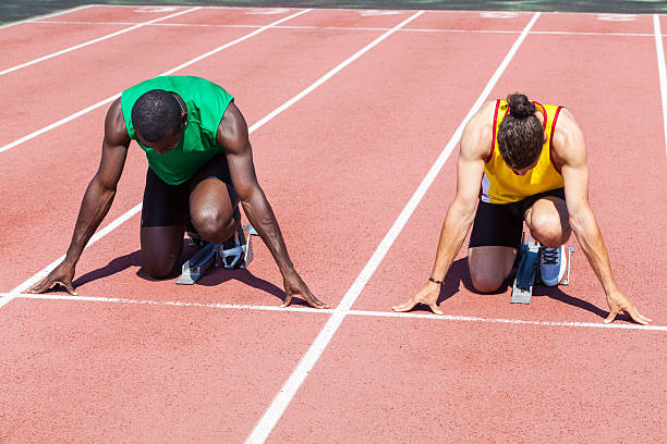 dois atletas pronto para começar a corrida - rivalry starting block track and field athlete track and field - fotografias e filmes do acervo