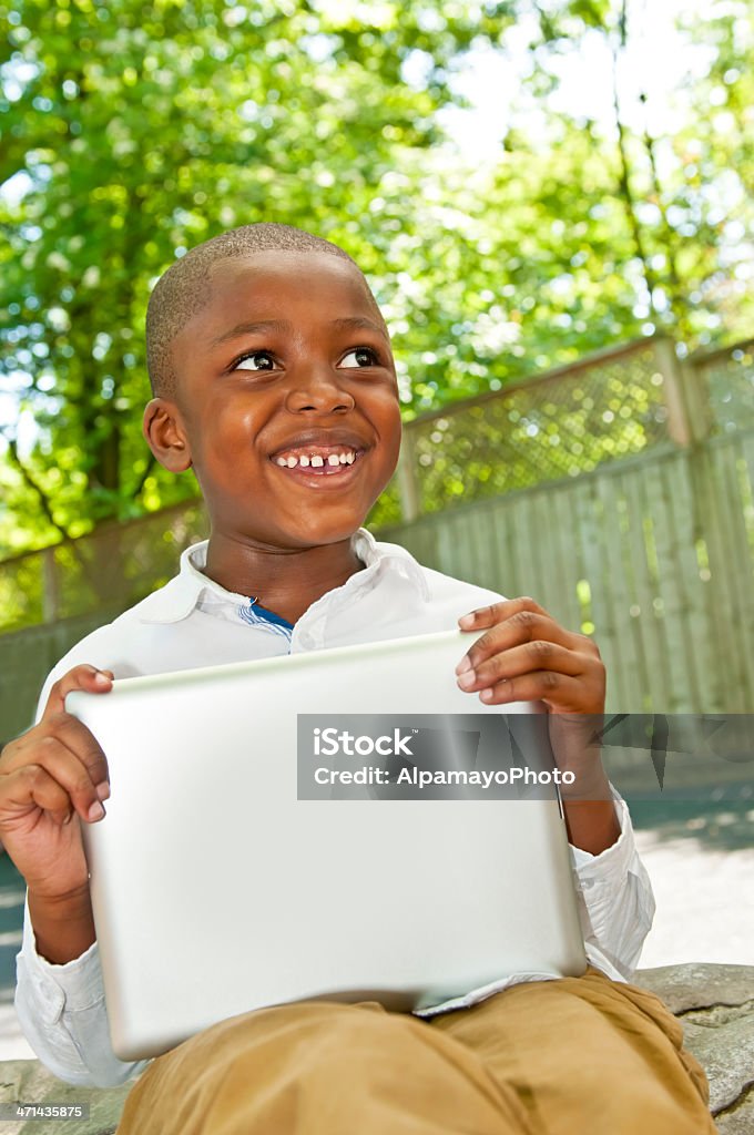 Little pre-school boy playing on tablet - III Little boy playing on tablet in the school backyard. African Ethnicity Stock Photo