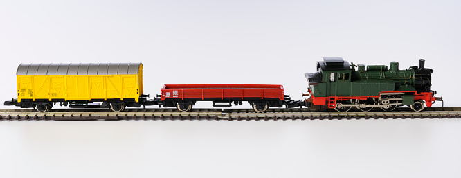 Vintage toy locomotive with railroad track on white background.