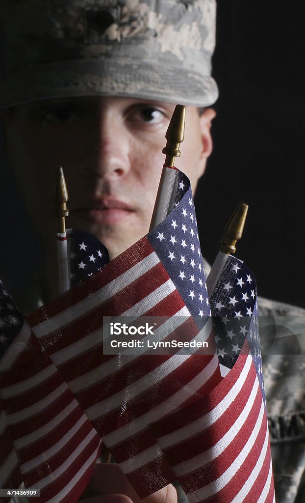 U.S. Soldier with American flags Low-key image of an active-duty U.S. soldier holding American flags US Veteran's Day Stock Photo