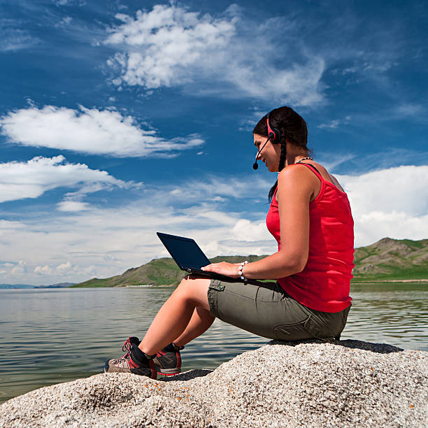 istock Young woman with laptop on the rock 471438399