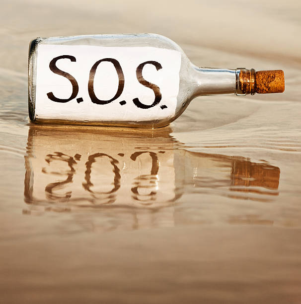 sos — говорит подавленный послание в бутылке в ресторане waters edge - stranded message in a bottle island document стоковые фото и изображения