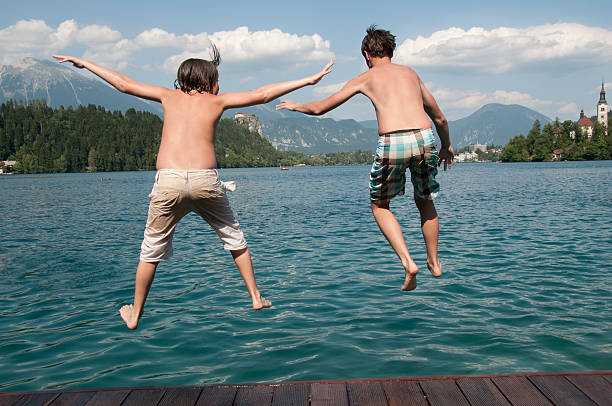 istock Two teenager boys jumping into a lake 471440357