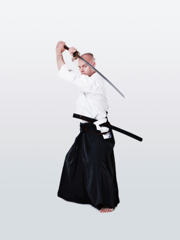 Focused martial arts swordsman holding his blade while isolated on white
