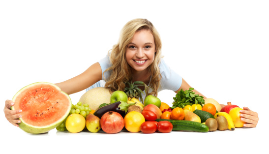 A cute young woman embracing a bunch of delicious fruit and vegetables