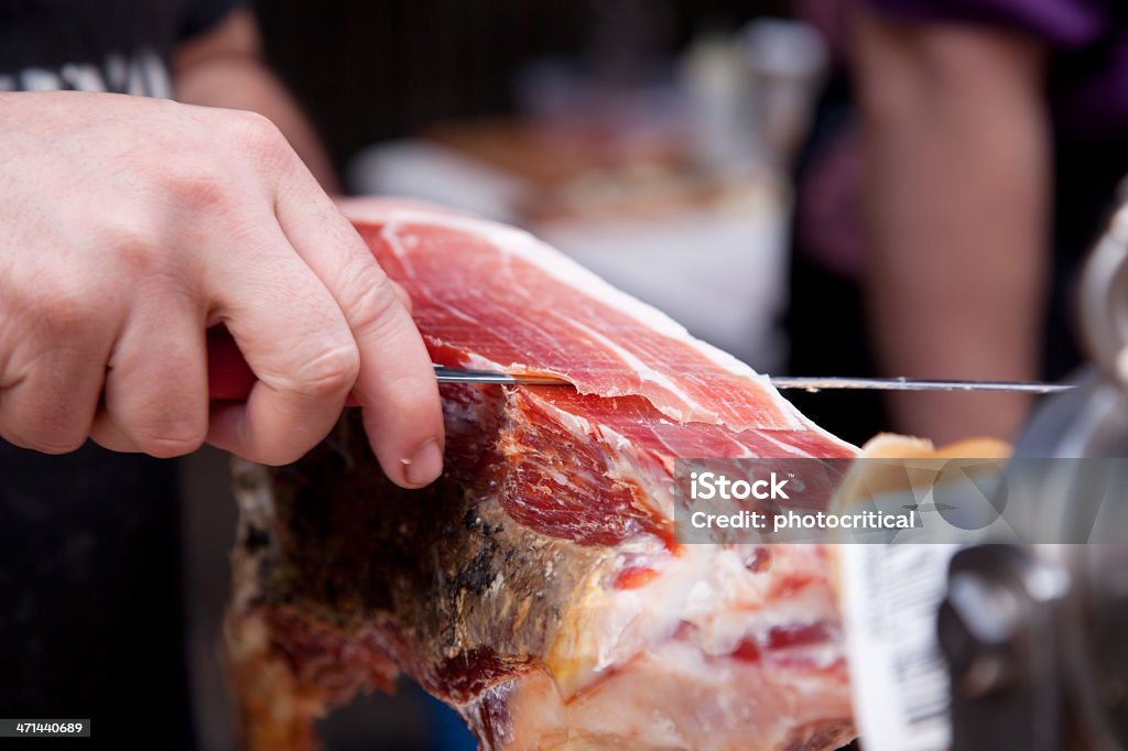 Slicing cured Ham Slicing cured Ham at a Delicatessen. Parma Ham Stock Photo