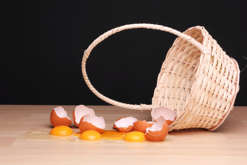 Broken eggs next to an overturned wicker basket.  Concept: 