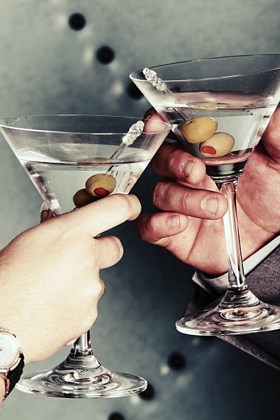 Martini Toast Two people make a toast with their martinis.  martini glass photos stock pictures, royalty-free photos & images