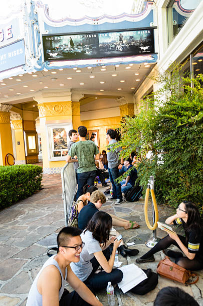 Waiting for "The Dark Knight Rises" Midnight Release Los Angeles, California, USA - July 19, 2012: People waiting in line at the entrance of the Fox Village Theatre since the afternoon for the midnight release of the movie "The Dark Knight Rises". theater marquee red carpet movie theater movie stock pictures, royalty-free photos & images