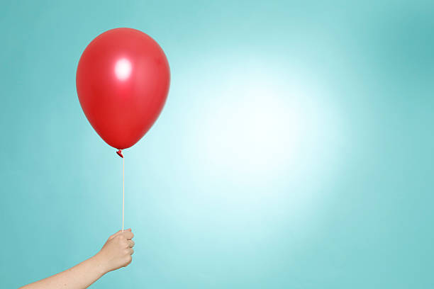 Hand holding a red helium balloon