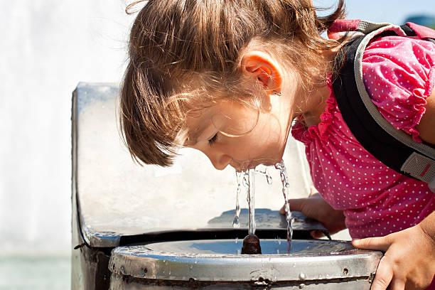 istock Young girl drinking from a water fountain 471445717