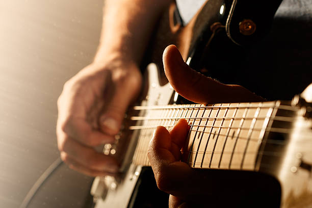 Close up of mans fingers playing electric guitar Hands of man playing electric guitar. Bend technique. Low key photo. string instrument stock pictures, royalty-free photos & images