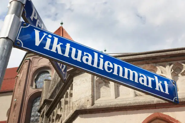 A street sign for the green market "Viktualienmarkt" in the center of Munich, Germany. In the background the back of the church St. Peter.