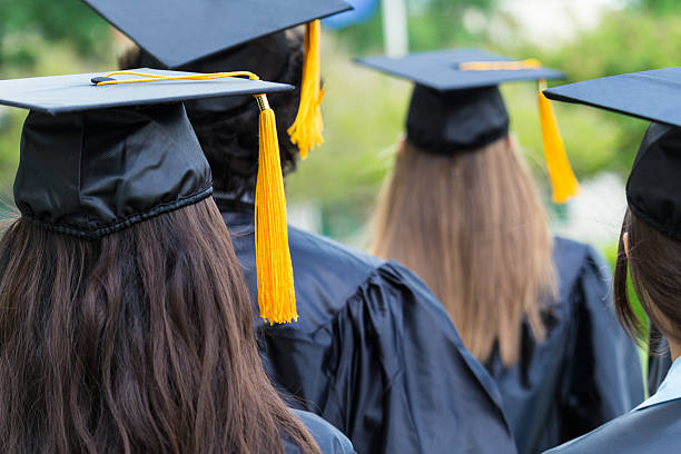 istock High school or college graduates walking across lawn 471449326