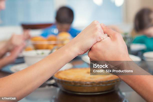 Mother Holding Daughters Hand While They Pray Over Meal Stock Photo - Download Image Now