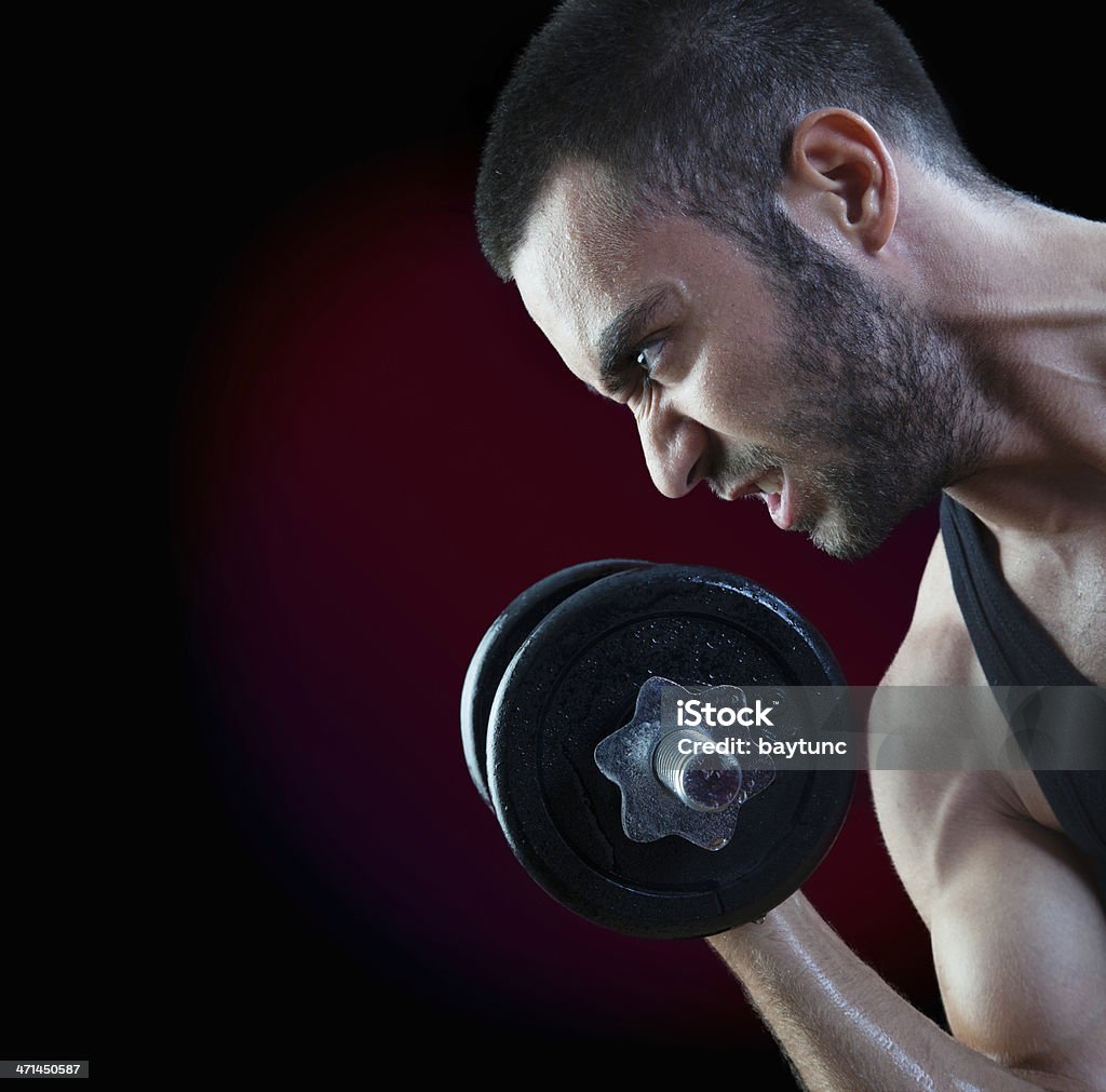 Grimacing man lifting weights Grimacing man lifting weights on red background Grimacing Stock Photo