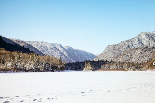 Jacques-Cartier National Park Winter Landscape featuring a frozen lake and distant forested mountains.