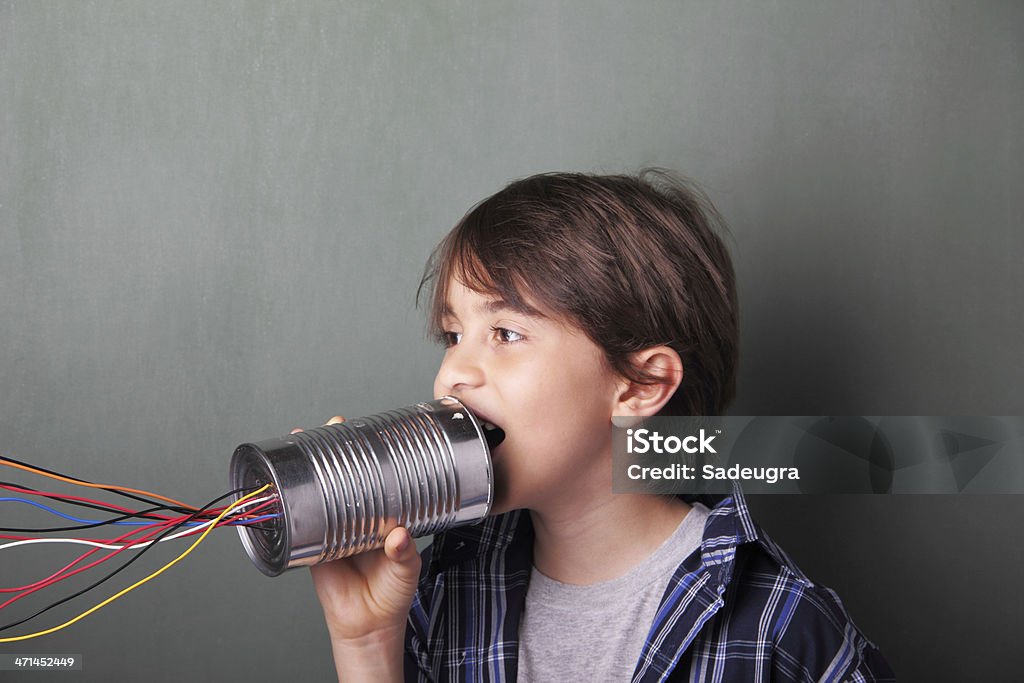 Boy talking into tin can with colored wires Boy with tin can telephone talking to his network of friends. Boys Stock Photo
