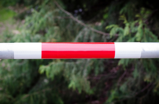 Closeup metal security bar with red and white reflector sticker against dark background, full frame horizontal composition with copy space