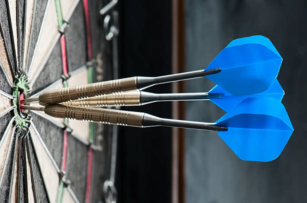 Dart board with three darts in the bulls eye