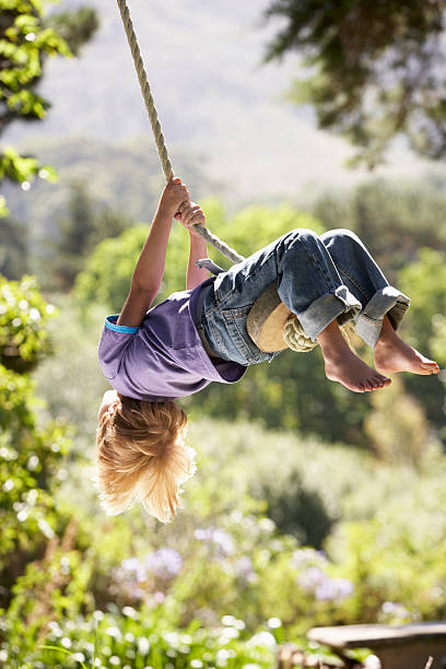 istock Young boy swinging on a rope tied from a tree 471457327