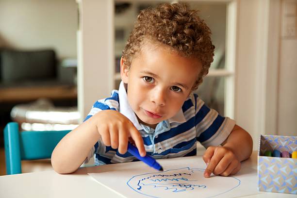 Charming toddler busy doing his art activity at his desk