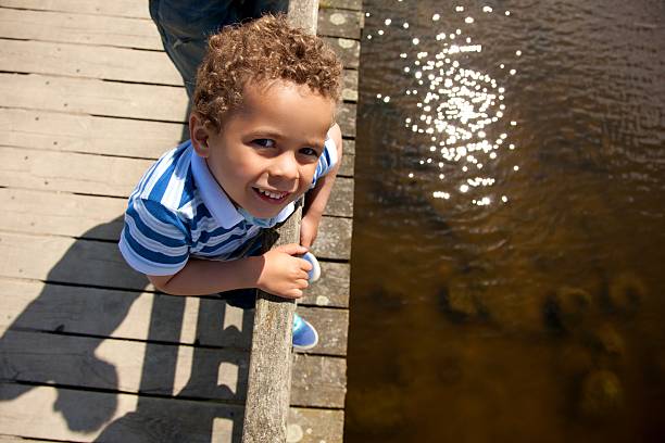 A smiling young girl enjoys swimming in a calm river with a scenic forest backdrop. The image captures the essence of summer fun and childhood joy in nature.