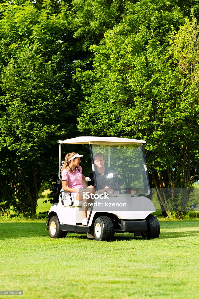 sportive joven pareja con cochecito de golf en un campo de golf - Foto de stock de Coche eléctrico - Coche alternativo libre de derechos