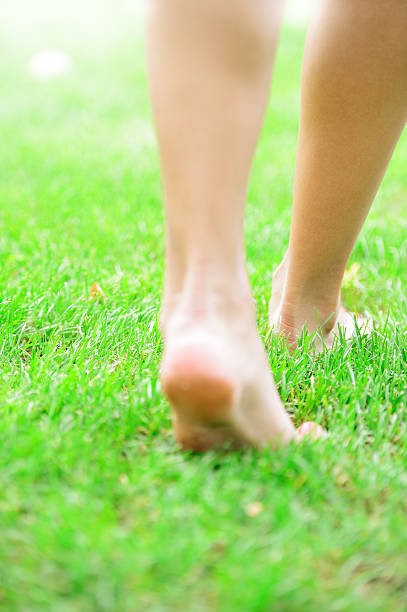 istock Woman with bare feet walking on grass 471472721